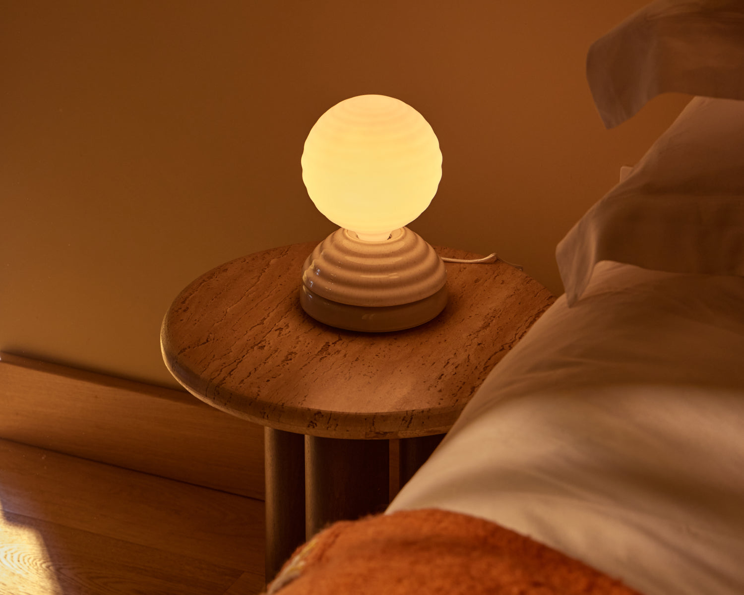 Wake Sleep Light in Pebble White on a bedside table in a warm, cosy bedroom setting