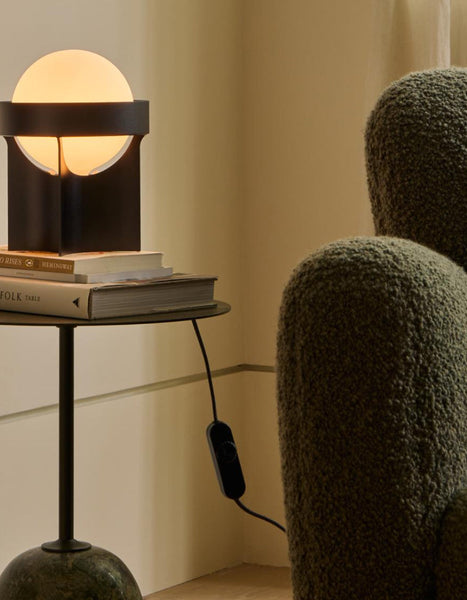 Loop Table Lamp in Dark Grey next to an armchair in a small living room setting