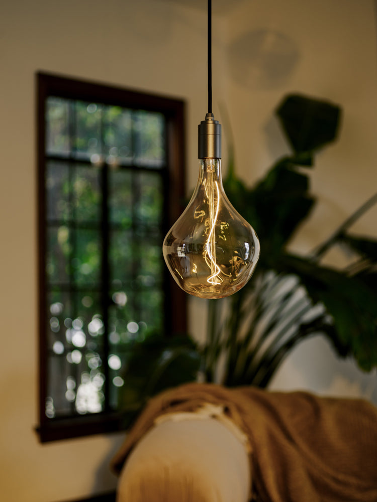 Our new Silver Pendant light paired with a Voronoi II bulb in a living room setting, bringing cosy warmth to the environment.